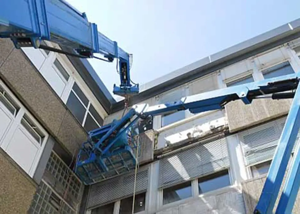 Ein mobiler Krandienst hebt Materialien in die oberste Etage eines Firmengebäudes